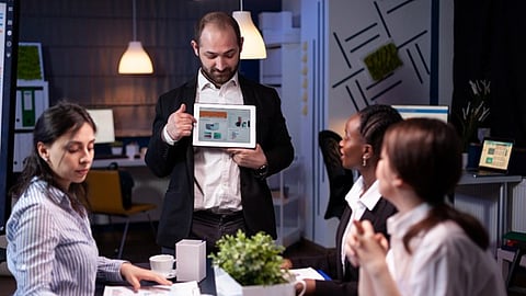 Team in office reviewing marketing presentation on tablet during collaborative meeting