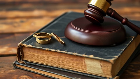 Gavel and wedding rings resting on book representing divorce and legal process