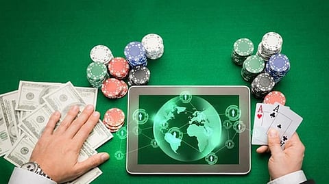 Hands with cash, chips, cards, and tablet showing digital casino interface on green table