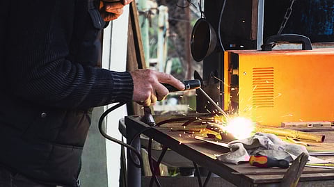 Technician welding metal with sparks in workshop setting