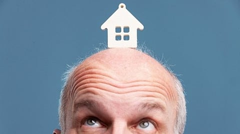 Man with house icon on head looking upward representing real estate thinking