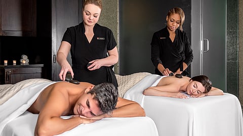 Couple receiving side-by-side hot stone massages in luxury spa room