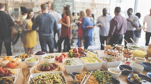 Buffet table with catered dishes and guests networking at corporate event