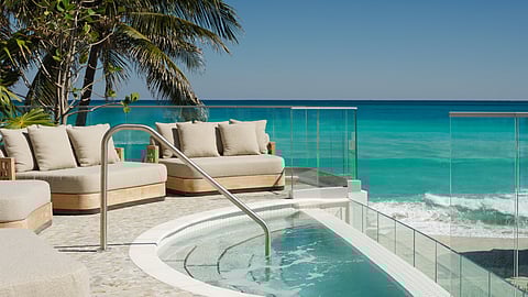 Oceanfront pool deck with hot tub, palm trees and lounge seating overlooking the beach