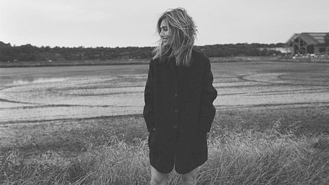 Veronica de Piante standing in grass near water in windblown portrait