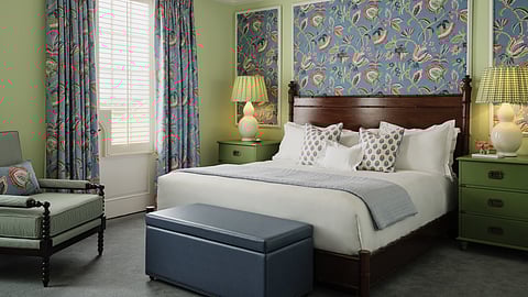 Spacious bedroom with patterned drapes, upholstered bench and floral accents