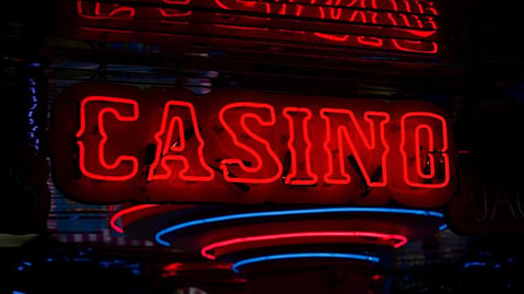 Red neon casino sign reflecting lights in a dark entertainment setting