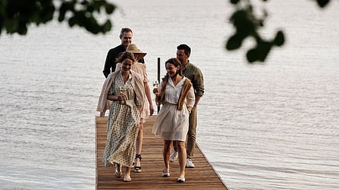 Group of travelers walking on wooden dock by calm Scandinavian lake
