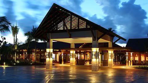 Resort entrance pavilion at dusk with illuminated columns and tropical architecture