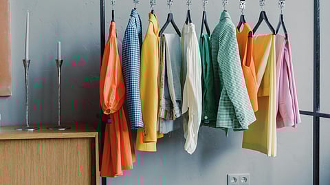 Colorful garments arranged on a clothing rack in a minimalist interior