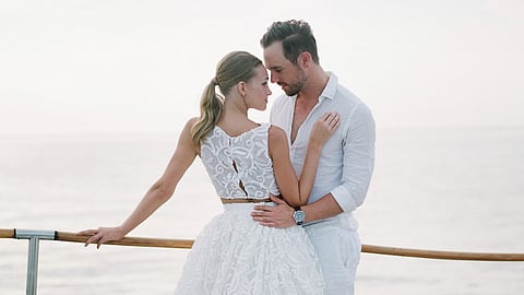 Couple embracing on yacht deck overlooking ocean at sunset
