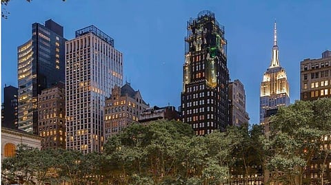 Evening at Bryant Park NYC with people on the lawn and the illuminated Empire State Building.