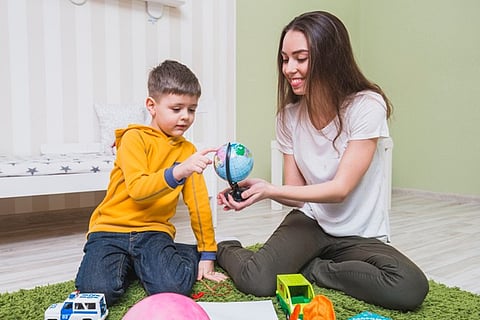 A woman and a young boy playing together on a green carpet