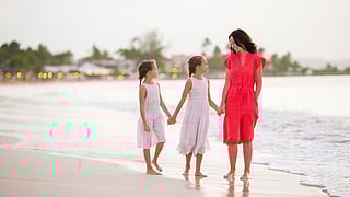 Mother and two daughters walking along a Miami beach at sunset
