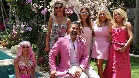 Guests in pink gather poolside at a Palm Beach luncheon with cherry blossom décor