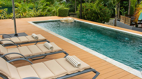 Modern pool deck with lounge chairs and tropical landscaping surrounding a rectangular swimming pool