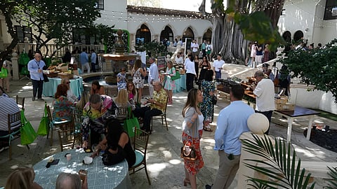 Crowd mingles around tables and a fountain in an outdoor courtyard setting at a food festival