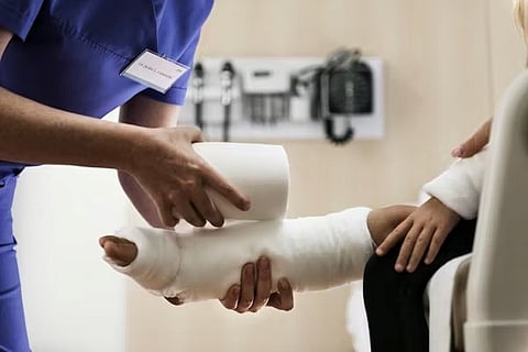 A medical professional applying a plaster cast to a child's leg to treat a broken bone