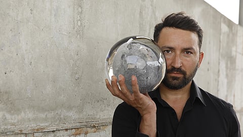 Portrait of Luca Gnizio holding a glass sphere symbolizing recycled materials and sustainability