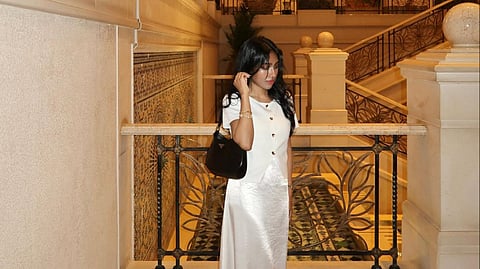 Lina Moynha in elegant white outfit standing in ornate luxury interior with arches and marble