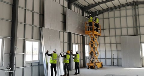 Construction workers installing insulated metal panels on the interior walls of a steel building