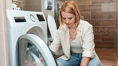 Woman doing laundry in a modern bathroom space
