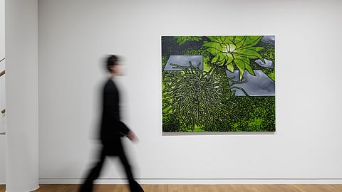 Blurred figure walking past a green-toned abstract painting in a gallery space 