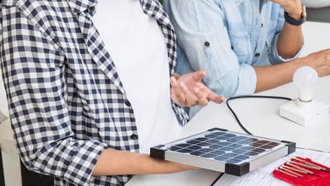 A woman examining a small solar panel 