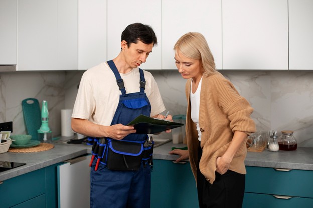 A repair technician interacting with a homeowner in a kitchen