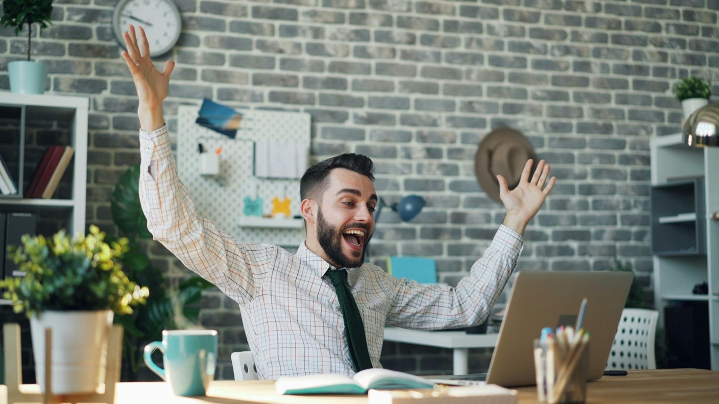 A person celebrating a success at their office desk