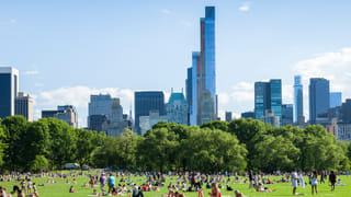 Crowds relaxing on the Sheep Meadow in Central Park with the Manhattan skyline in the background
