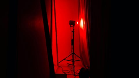 Red light therapy device glowing in a dark studio space with equipment visible