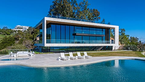 A contemporary glass hillside estate with pool overlooking landscaped grounds