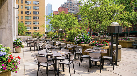 Outdoor dining terrace at The Consulate NYC with lush greenery, floral planters, and city backdrop