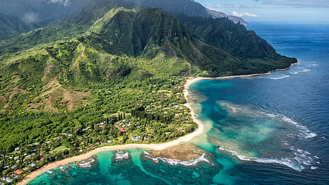 Aerial view of Kauai’s Napali Coast with emerald cliffs and turquoise shoreline