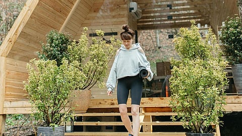 Woman steps outside a modern A-frame cabin in the woods