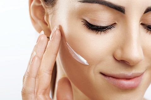 a close-up of a person applying a sunscreen