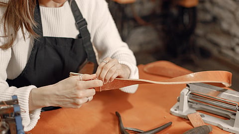 Craftsperson shaping leather by hand at a custom shoe workshop