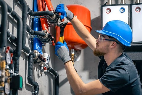 a person inspecting a commercial plumbing and heating system