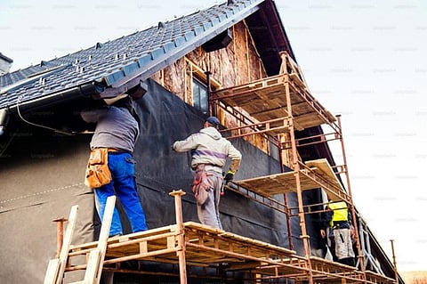 construction workers thermally insulating a house facade with glass wool and black foil
