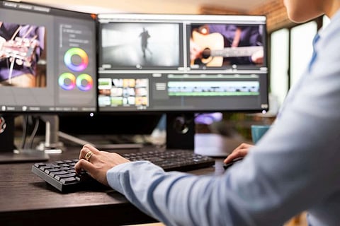 a person using dual computer monitors to edit a video project