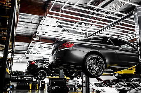 black BMW M4 features a matte finish and is elevated on a hydraulic car lift