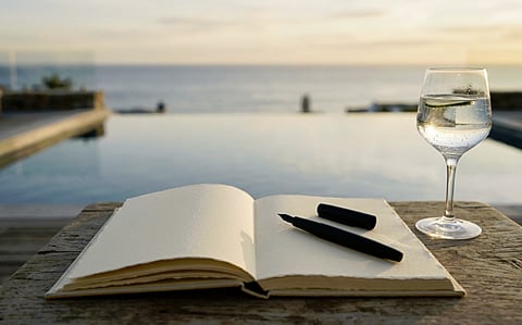 a stylized stock photo featuring a blank notebook and a black pen resting on a rustic wooden table