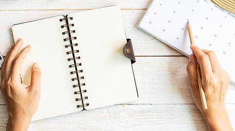 Person using a planner and calendar to organize holiday schedules and activities