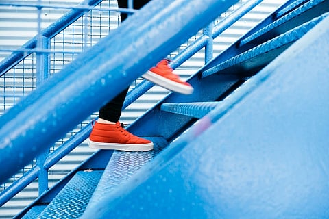vibrant red sneakers climbing a bright blue metallic staircase