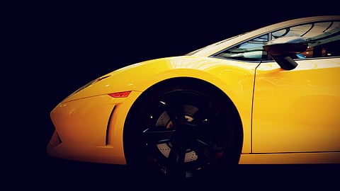 Yellow luxury sports car showcased in a studio-style setting against a dark background.