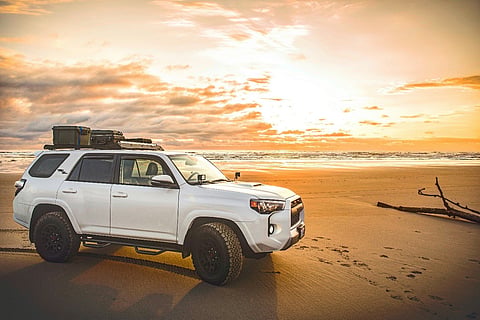 a white Toyota 4Runner featuring a roof rack loaded with storage cases