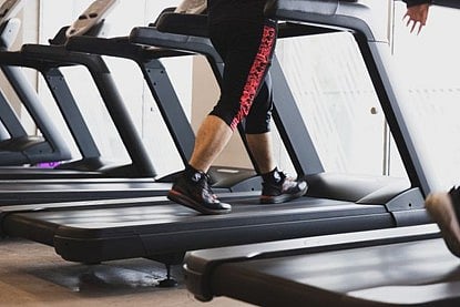 Person's legs running on a treadmill in a gym.