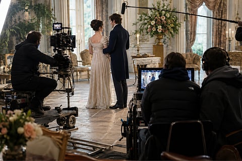 Film crew shooting a period drama scene with actors in a wedding-style setup.