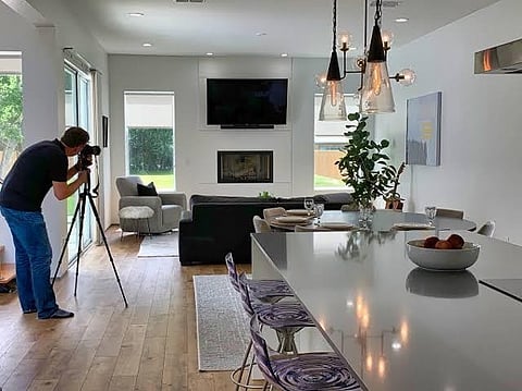 Person photographing a modern home interior with a camera on a tripod